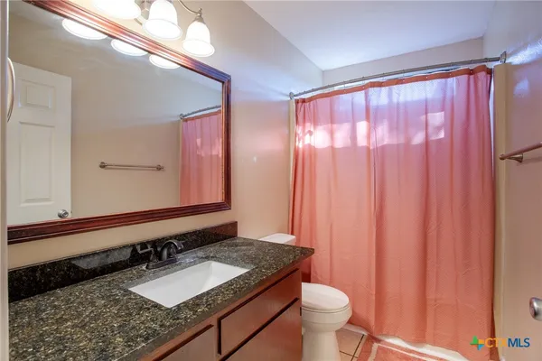 a bathroom with a granite countertop sink and a mirror