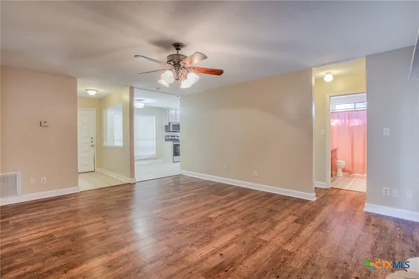 a view of an empty room with wooden floor and a window