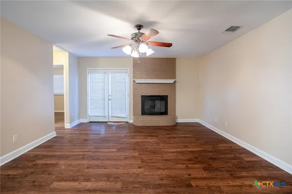 a view of an empty room with chandelier fan and fire place