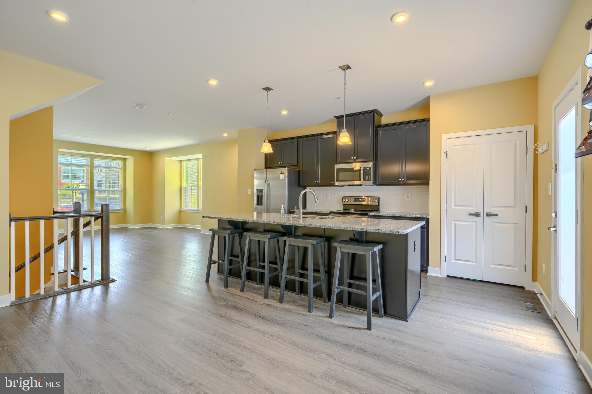7113 Foundry Mews Baltimore, MD 21222 - Photo 10 of 29 a kitchen with stainless steel appliances granite countertop a stove top oven a sink a refrigerator with grey cabinets and wooden floor