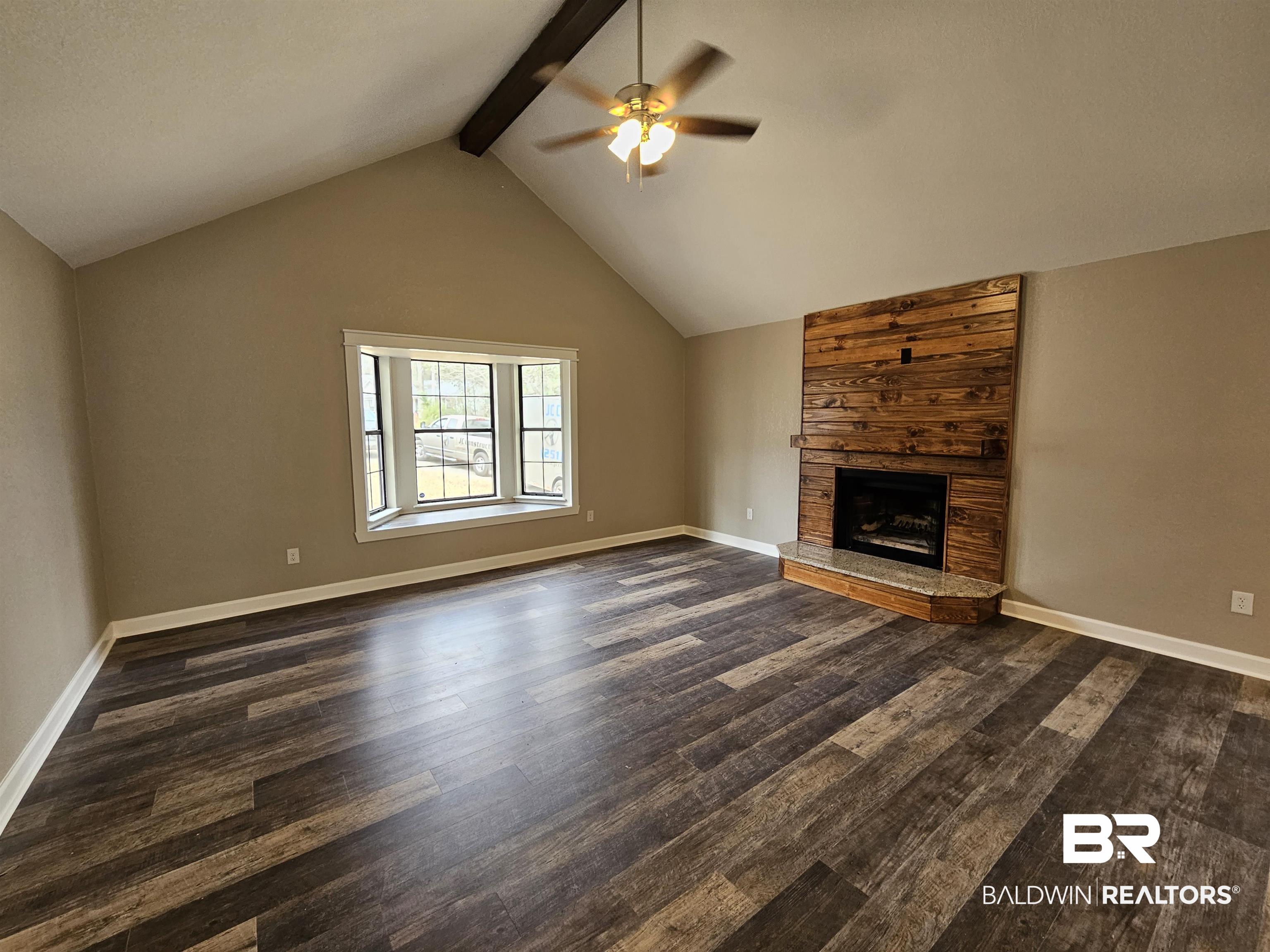 138 Wicker Way Daphne, AL 36526 - Photo 8 of 32 Unfurnished living room with dark wood-style flooring, a ceiling fan, and a large fireplace