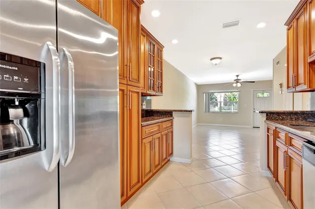 a kitchen with stainless steel appliances granite countertop a refrigerator a stove and a sink with wooden floor