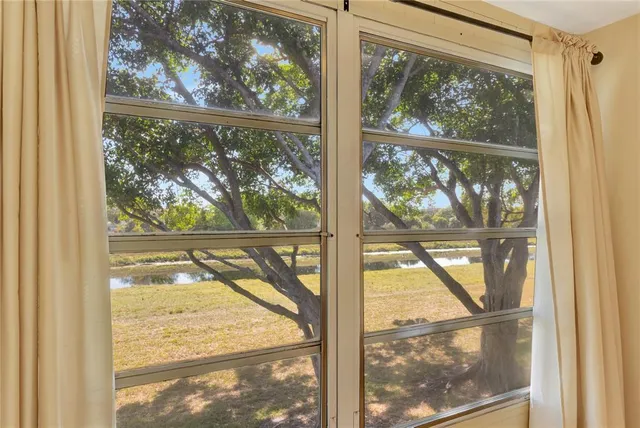 a view of an empty room with wooden floor and windows