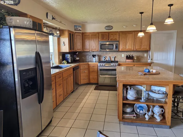 a kitchen with stainless steel appliances granite countertop a refrigerator a stove and a sink