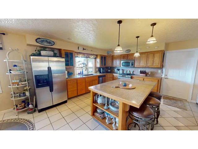 a open kitchen with stainless steel appliances kitchen island granite countertop a refrigerator a stove a sink and a microwave