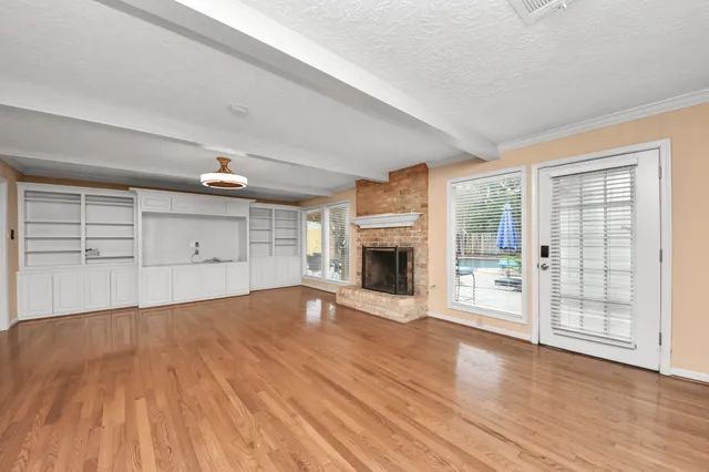 a view of empty room with wooden floor and fireplace