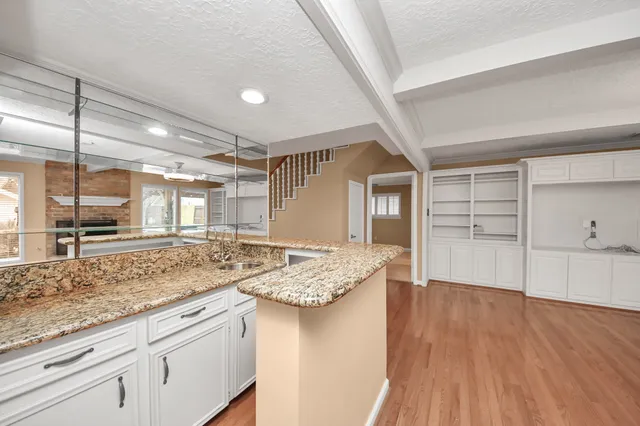 a open kitchen with kitchen island a sink stove and wooden floors