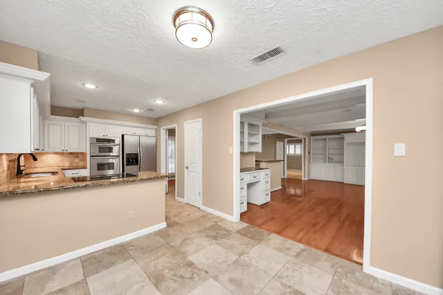 a view of living room kitchen with stainless steel appliances cabinets