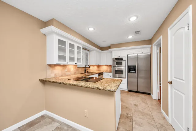 a kitchen with stainless steel appliances granite countertop a sink and a refrigerator