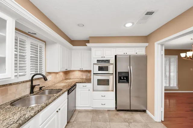 a kitchen with granite countertop a refrigerator and wooden cabinets