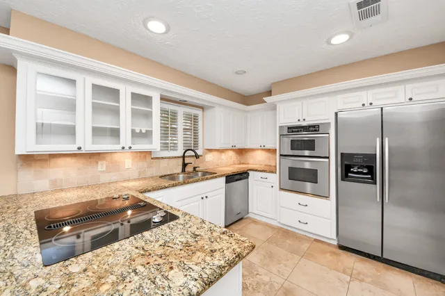a kitchen with granite countertop white cabinets and stainless steel appliances
