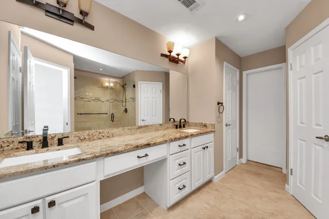 a bathroom with a granite countertop sink a mirror and a shower