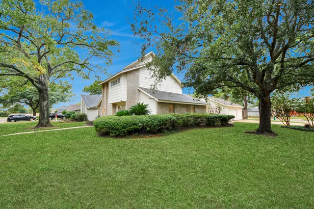 a view of a house with a big yard and large trees