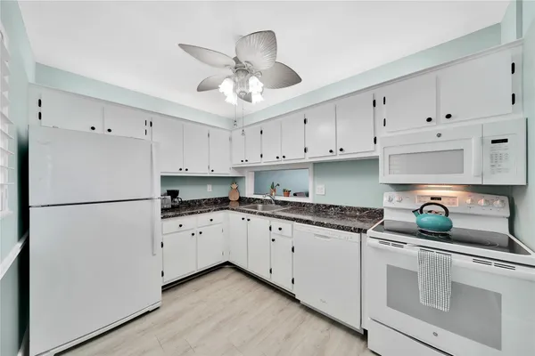 a kitchen with granite countertop white cabinets and white stainless steel appliances