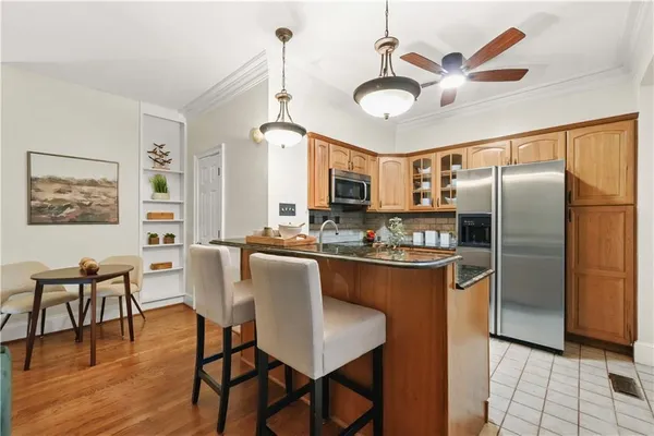 a kitchen with stainless steel appliances granite countertop a dining table chairs refrigerator and cabinets