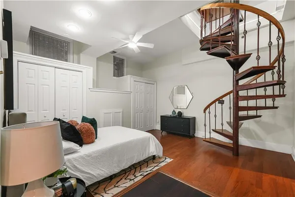 a bedroom with a bed a dresser and wooden floor