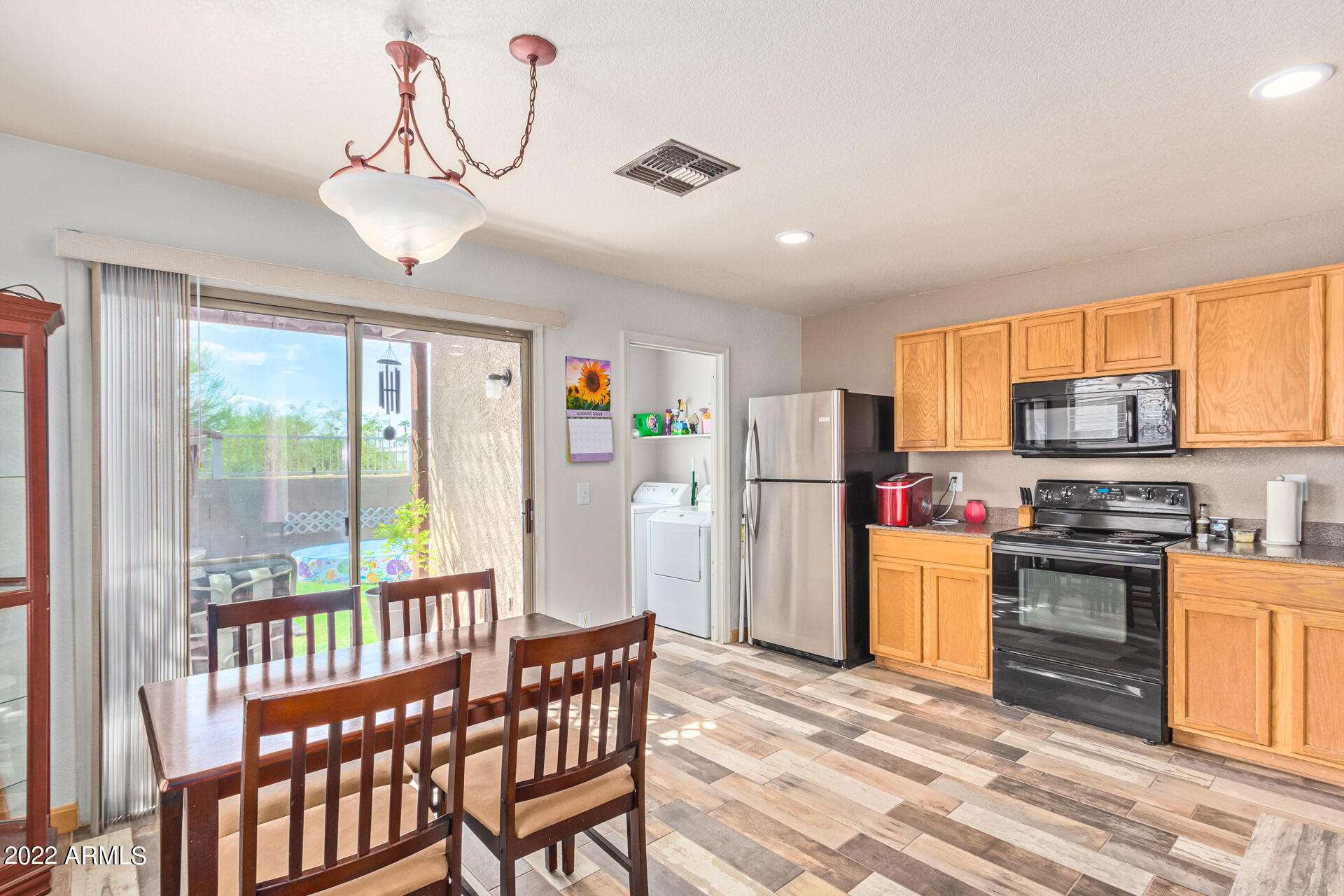 3466 South Chaparral Road Apache Junction, AZ 85119 - Photo 7 of 29 a kitchen with stainless steel appliances granite countertop a refrigerator a stove top oven and a dining table with wooden floor