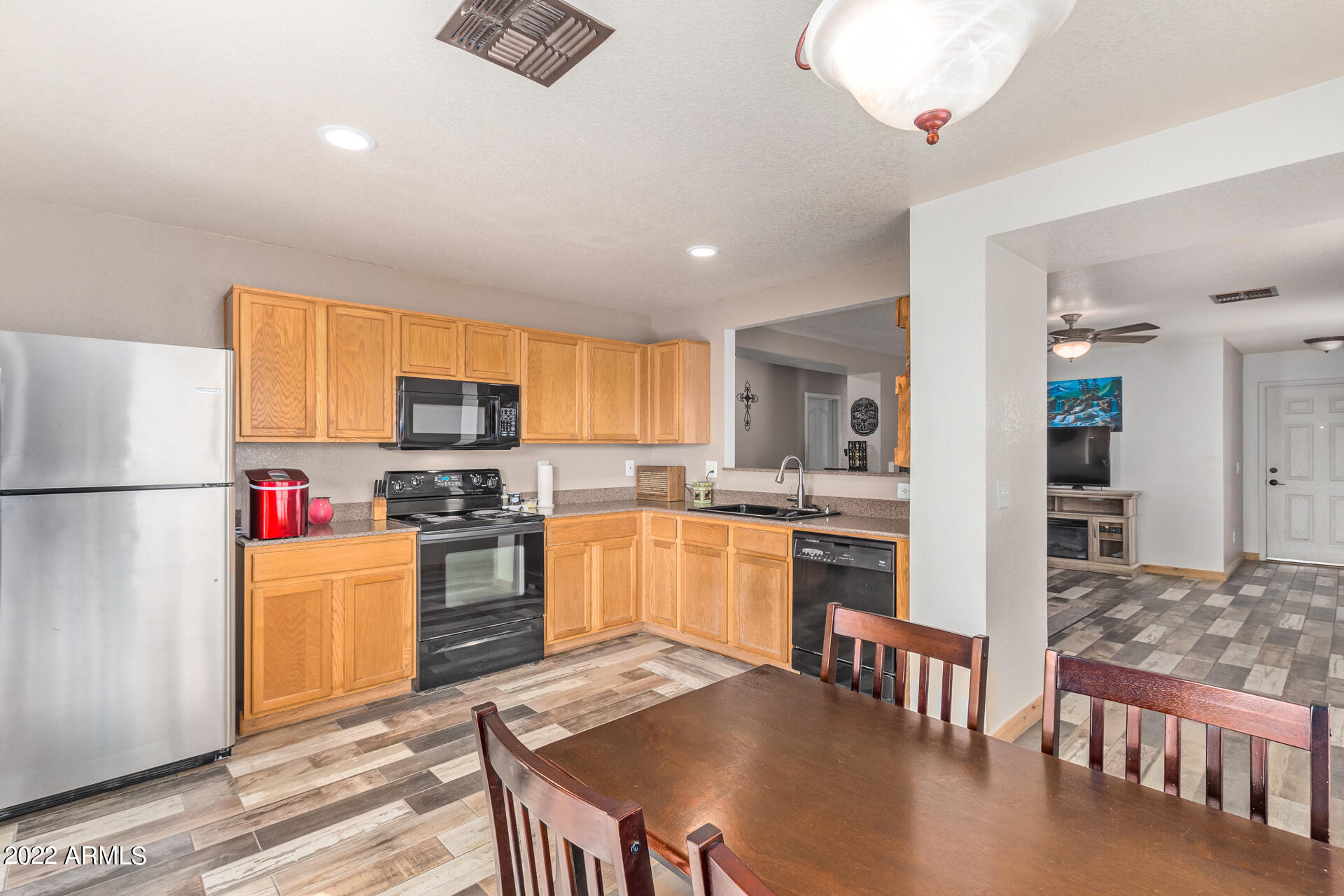 3466 South Chaparral Road Apache Junction, AZ 85119 - Photo 9 of 29 a kitchen with stainless steel appliances granite countertop a refrigerator a stove top oven a sink dishwasher and white cabinets with wooden floor