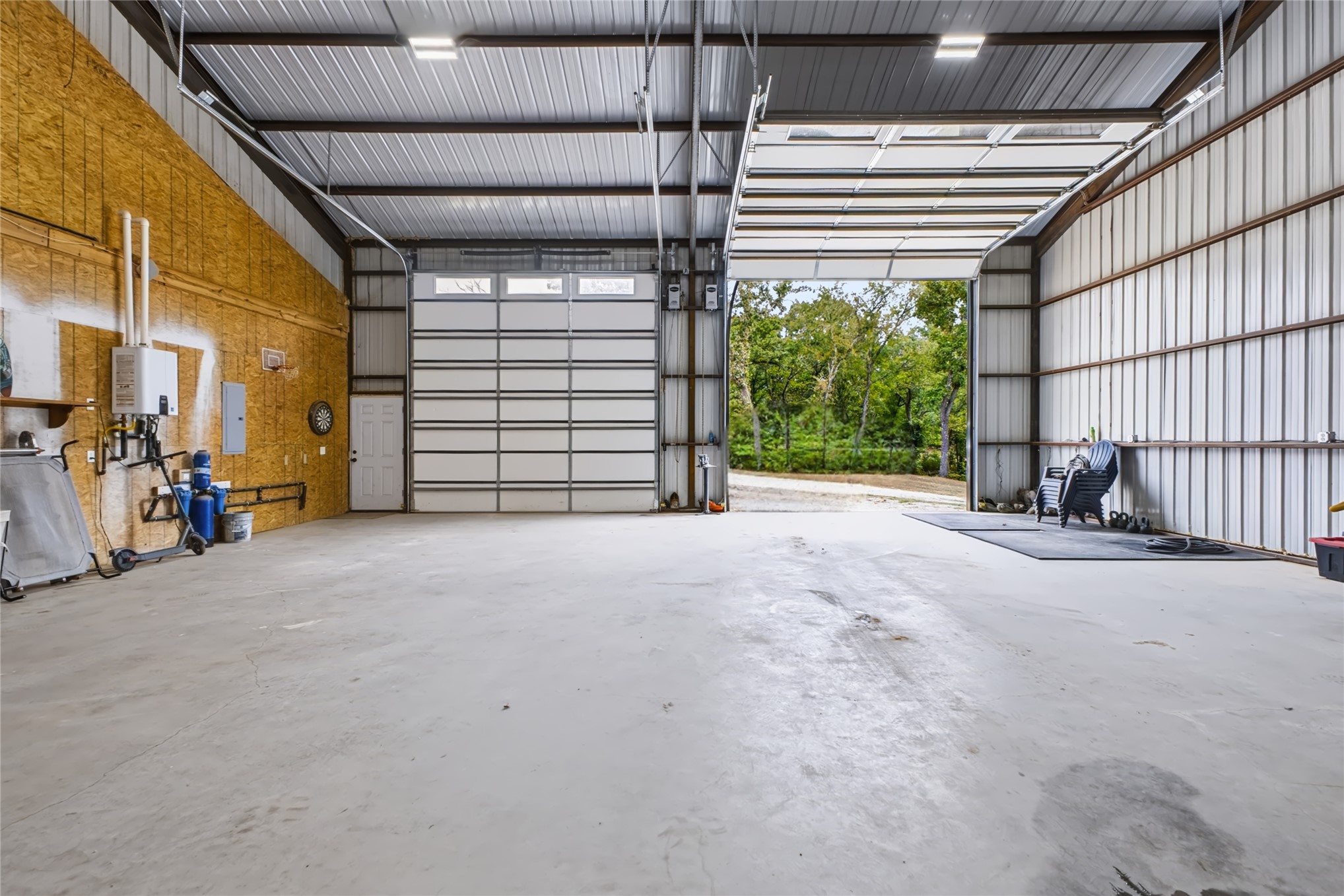 3607 South Half Bank Road Atoka, OK 74525 - Photo 39 of 82 Spacious metal-frame structure with concrete flooring, multiple overhead lighting fixtures, and two large overhead doors
