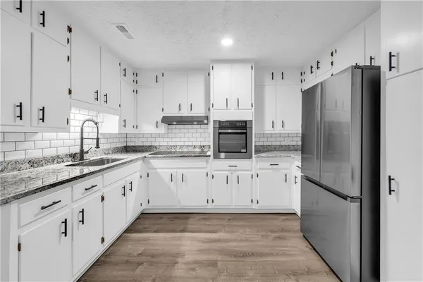 a kitchen with granite countertop white cabinets and stainless steel appliances