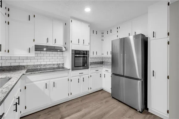 a kitchen with granite countertop white cabinets white stainless steel appliances and wooden floors