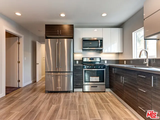 a kitchen with granite countertop a refrigerator and a stove top oven