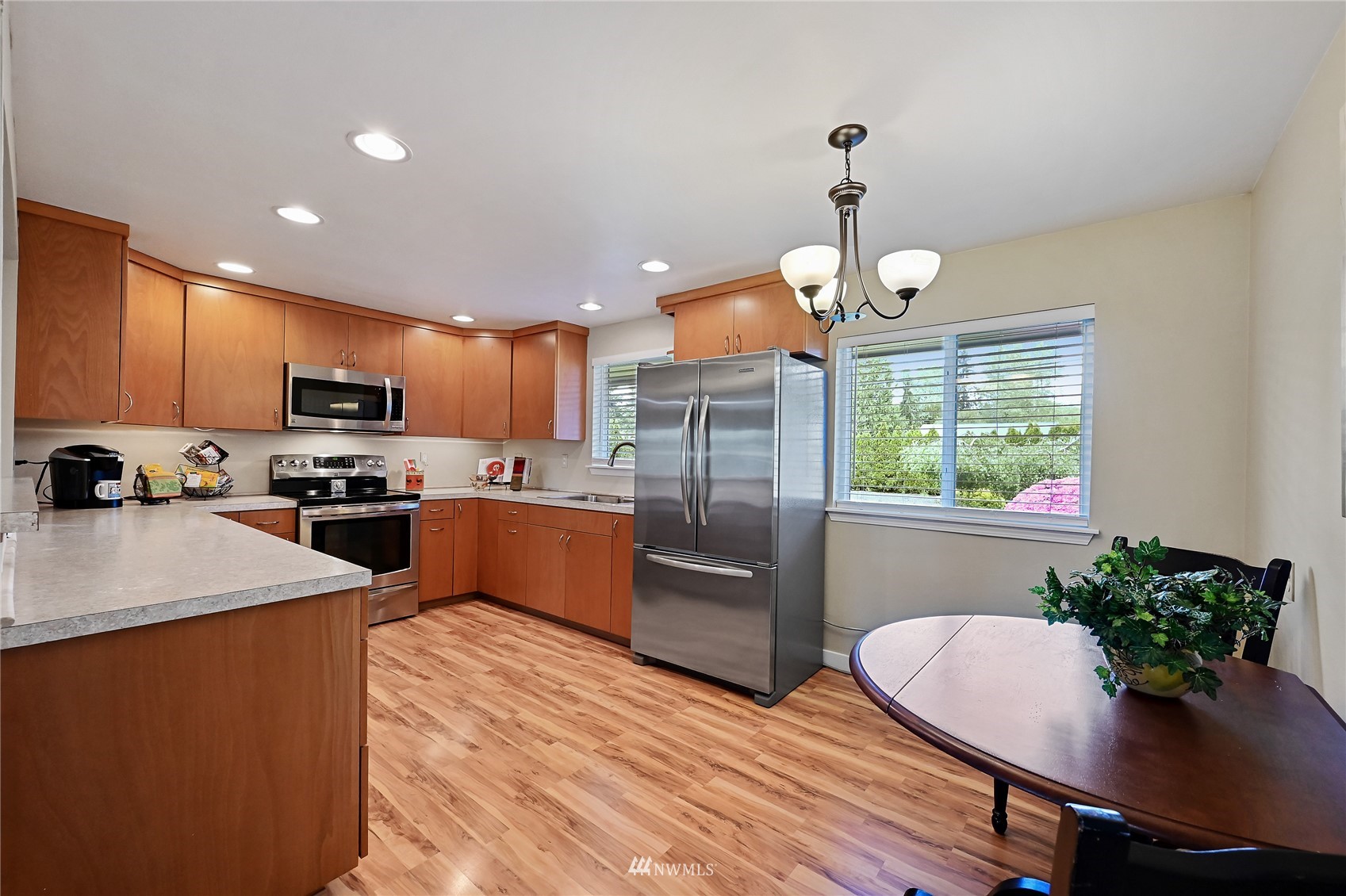 17341 Southeast 134th Street Renton, WA 98059 - Photo 9 of 36 a kitchen with granite countertop a refrigerator a stove a sink dishwasher a dining table and chairs with wooden floor