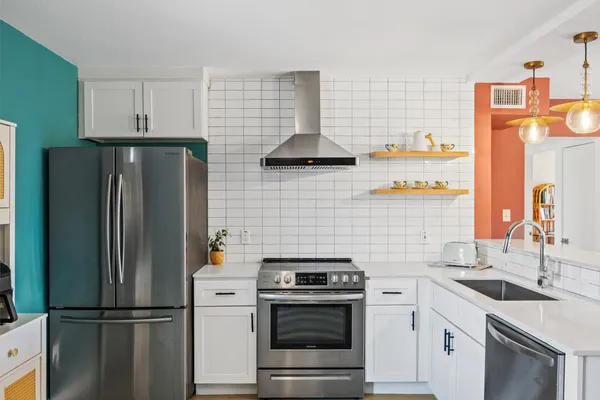 a kitchen with stainless steel appliances granite countertop a refrigerator a stove and a sink with wooden floor