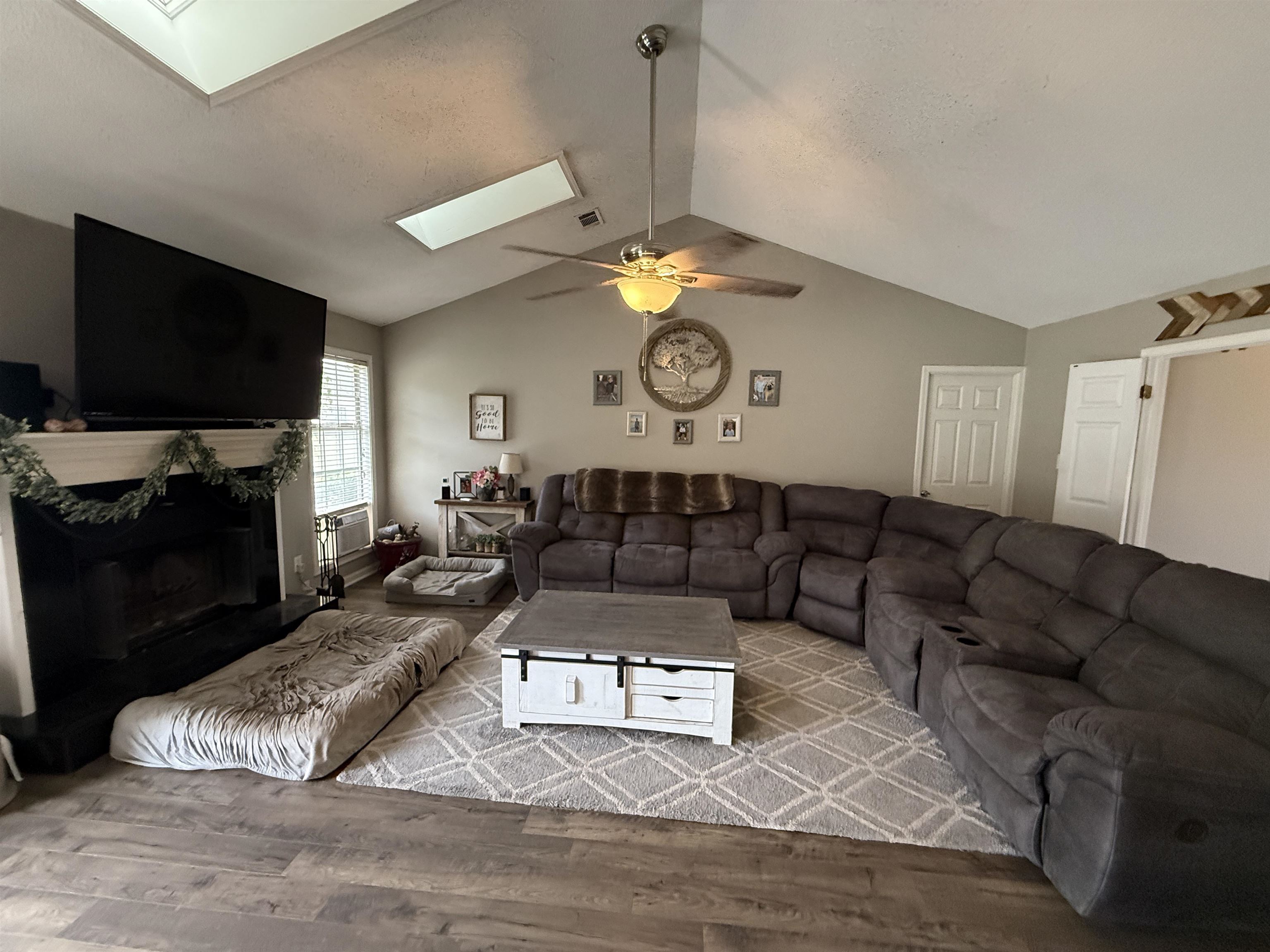 663 Tracy Road Millington, TN 38053 - Photo 8 of 21 Living area with vaulted ceiling, light wood finished floors, a skylight, a high end fireplace, and ceiling fan