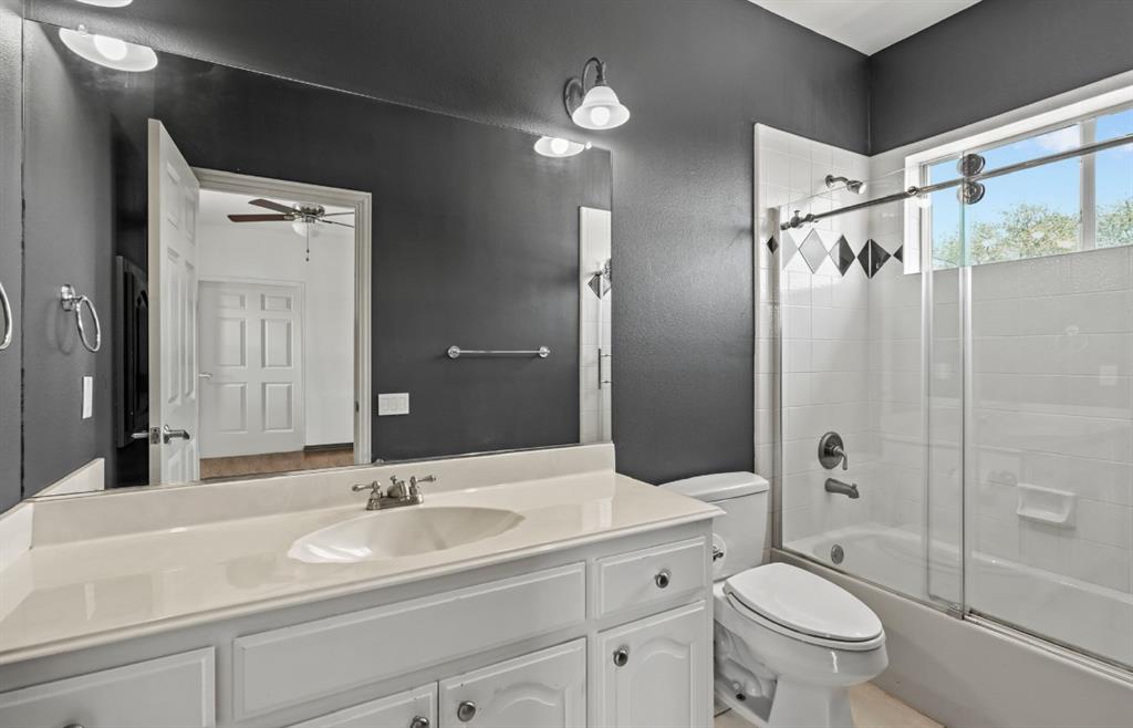 11911 Edgestone Road Dallas, TX 75230 - Photo 28 of 40 Full bathroom with vanity, combined bath / shower with glass door, and a ceiling fan