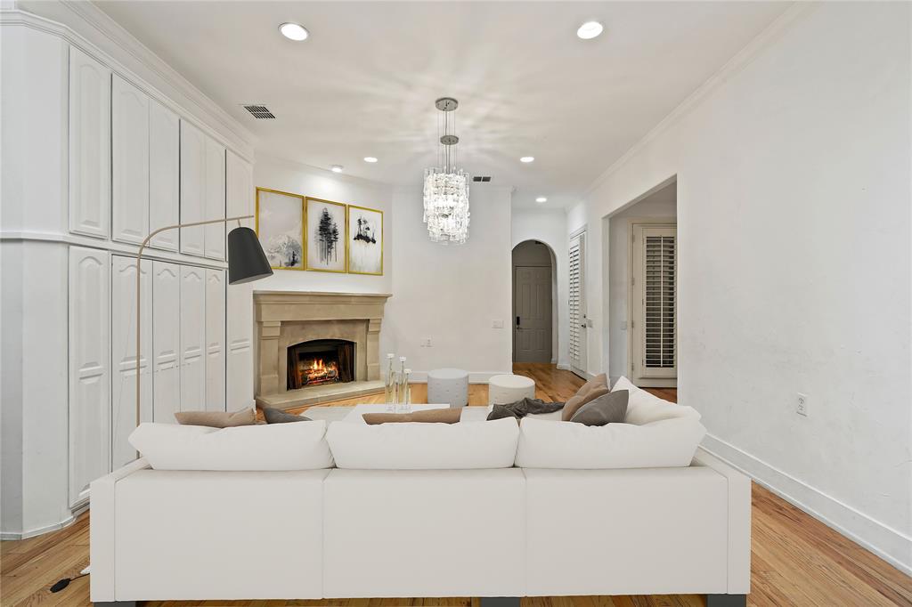 11911 Edgestone Road Dallas, TX 75230 - Photo 7 of 40 Living area with arched walkways, recessed lighting, light wood-type flooring, a warm lit fireplace, and a chandelier