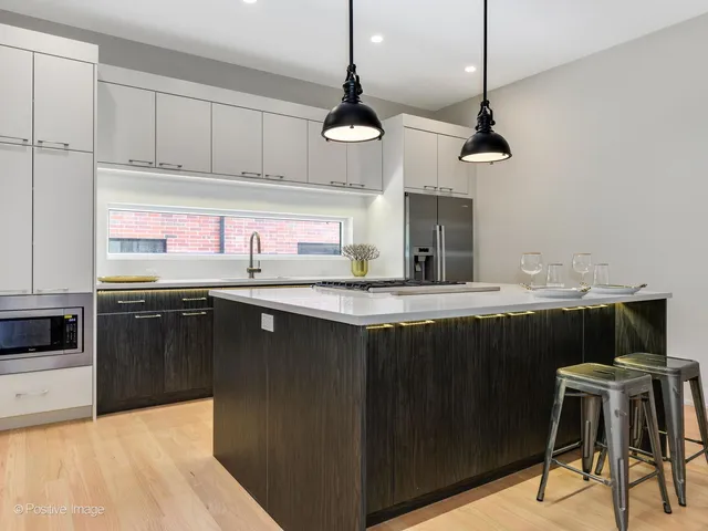 a kitchen with stainless steel appliances granite countertop a sink a stove a refrigerator and chairs