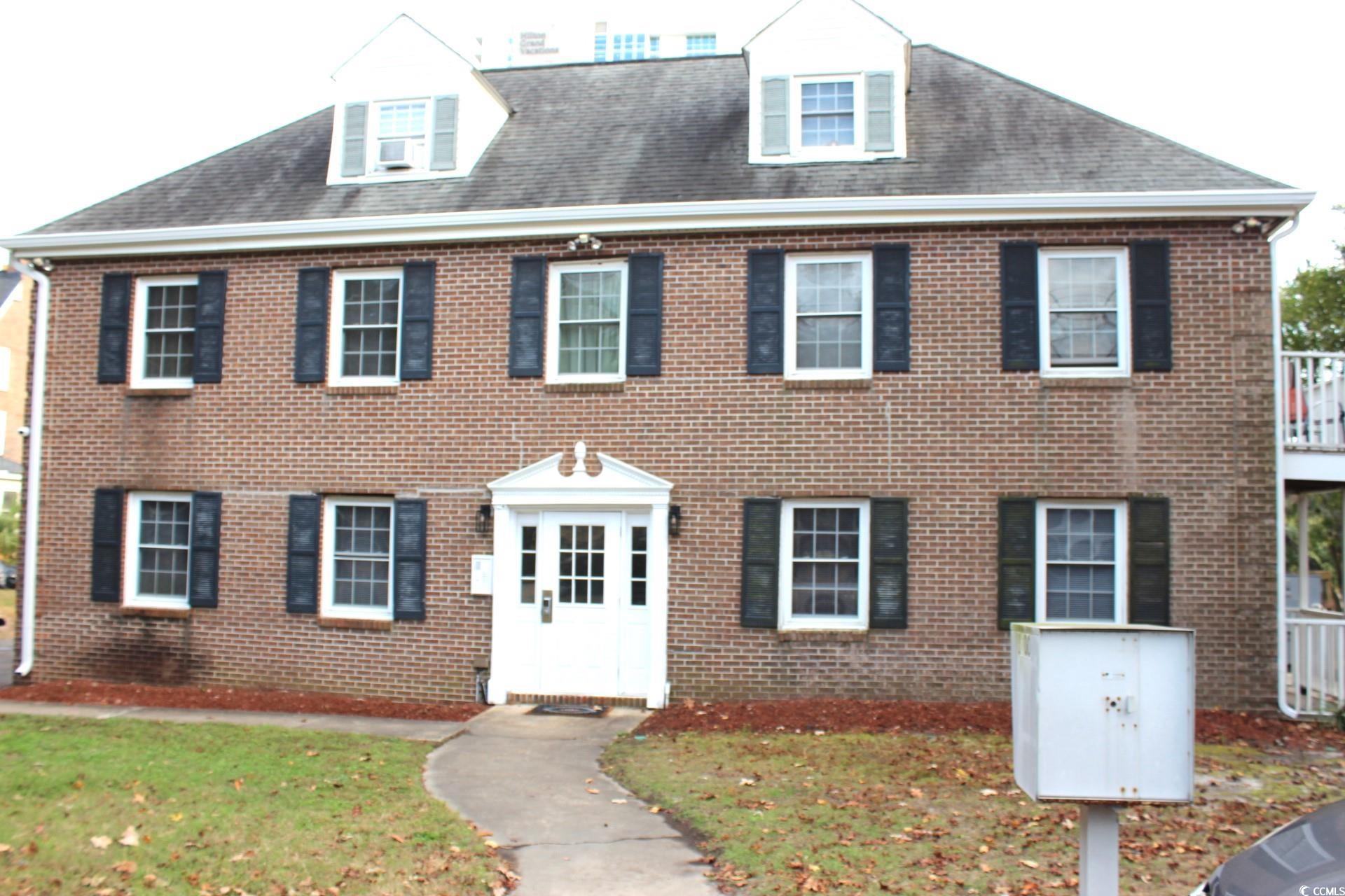Colonial house featuring brick siding and a front lawn