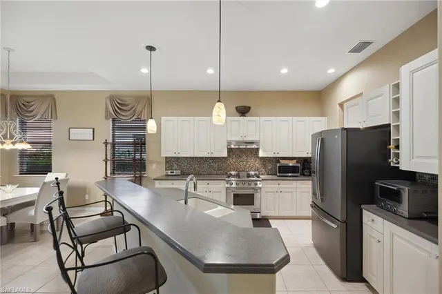 a kitchen with stainless steel appliances granite countertop a sink a stove a refrigerator cabinets and chairs