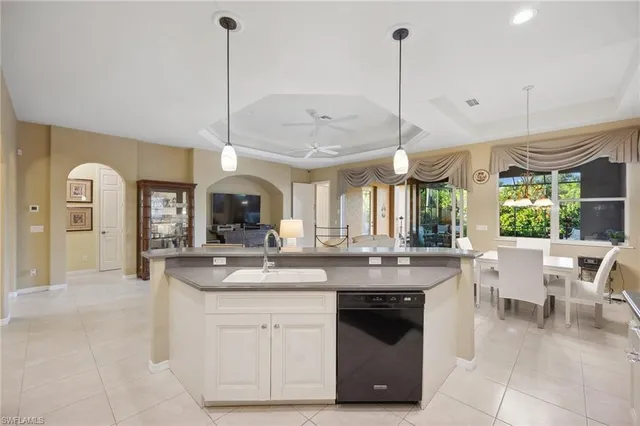 a kitchen with stainless steel appliances granite countertop a stove a sink and a dining table with white cabinets