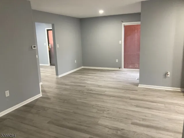 a view of an empty room with wooden floor and closet