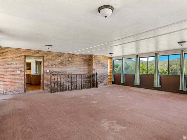 15680 North Beaver Dam Road Collinston, UT 84306 - Photo 21 of 49 Spacious room featuring a full wall of windows offering a mountain backdrop, exposed brick details, and a built-in bookshelf
