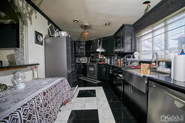 a kitchen with stainless steel appliances granite countertop a refrigerator a sink dishwasher a stove and white countertops with wooden floor