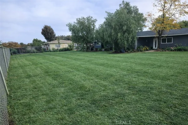 a view of house with yard and trees in the background