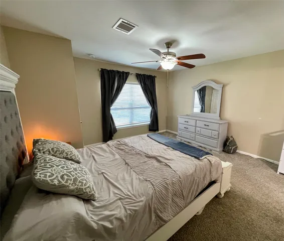 a bedroom with a bed ceiling fan and a window