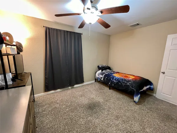 a bedroom with a bed and a flat tv screen on the dresser