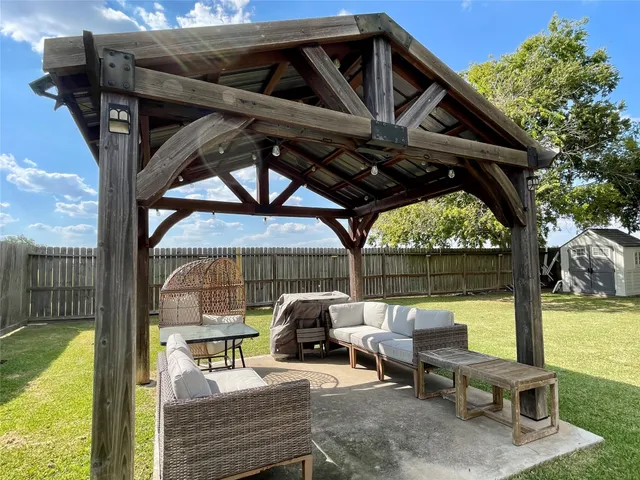 a view of a roof deck with table and chairs a barbeque with wooden floor and fence