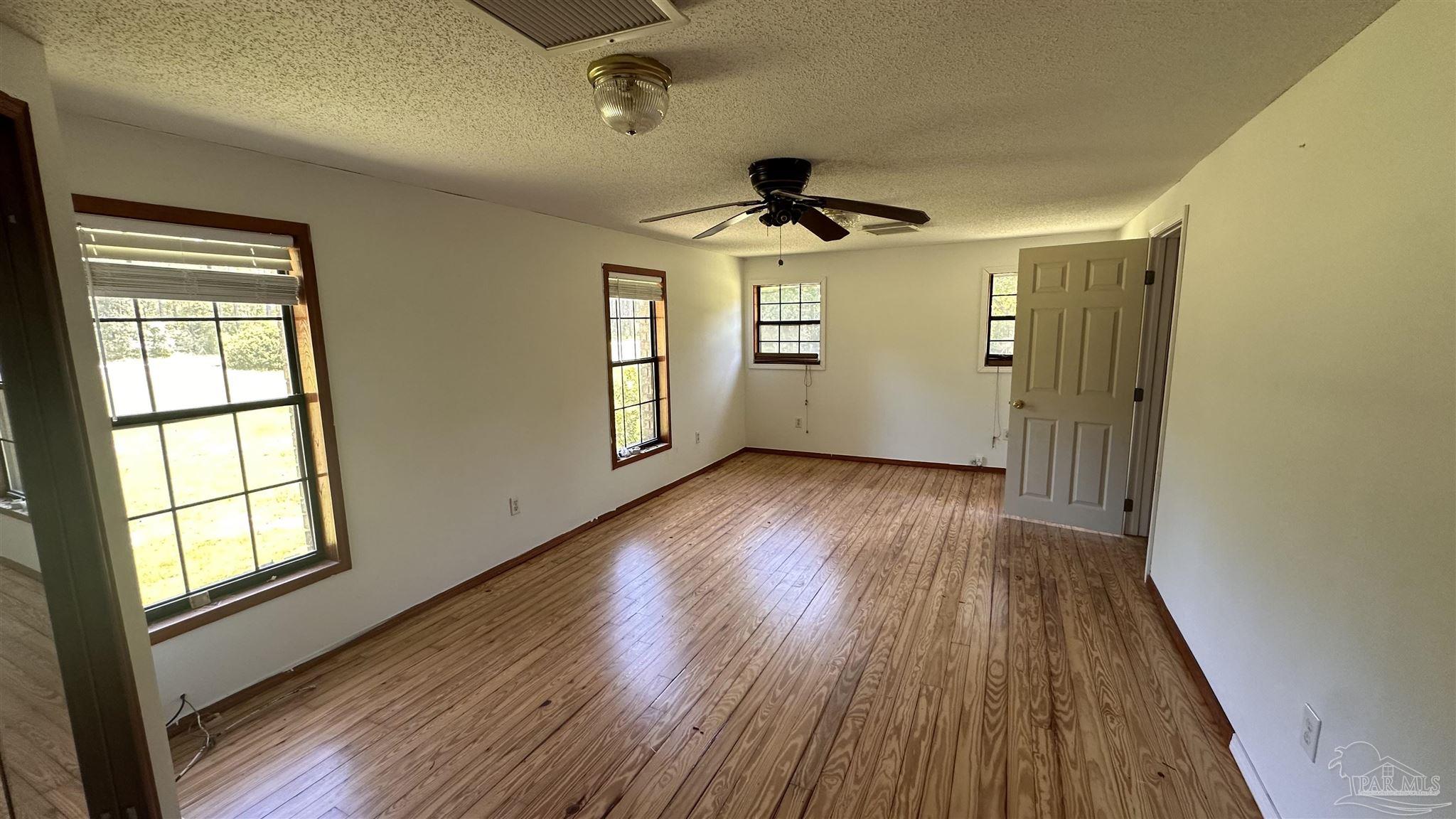 9353 Sellersville Road Jay, FL 32565 - Photo 16 of 26 a view of empty room with wooden floor and fan