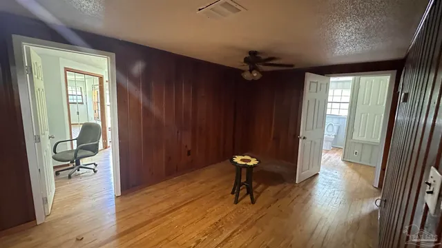 a view of empty room with wooden floor and fan