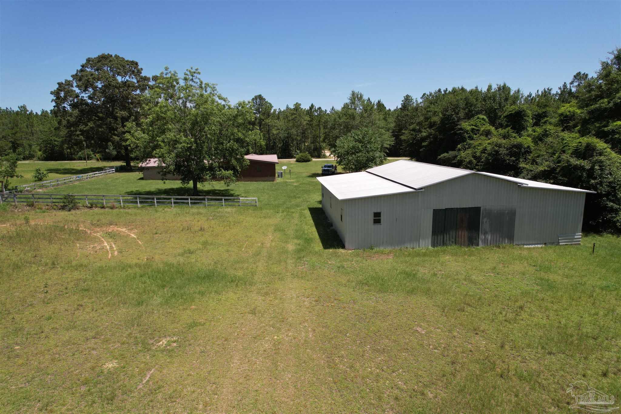 9353 Sellersville Road Jay, FL 32565 - Photo 20 of 26 a backyard of a house with lots of green space and trees in the background