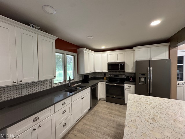 620 Ravenna Road Newton Falls, OH 44444 - Photo 3 of 23 Well-appointed kitchen featuring white cabinetry, dark countertops, a mosaic tile backsplash, and light wood-finish flooring