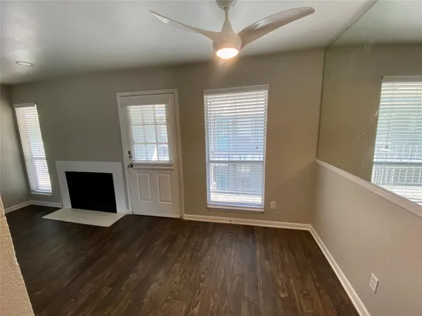 an empty room with wooden floor cabinet and windows