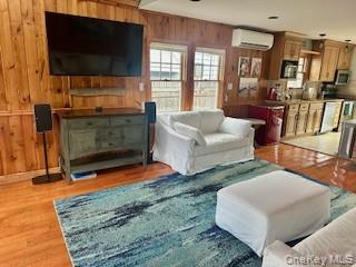 19 Ocean Road Ocean Beach, NY 11770 - Photo 6 of 20 Living area with wood finished floors, wooden walls, and an AC wall unit
