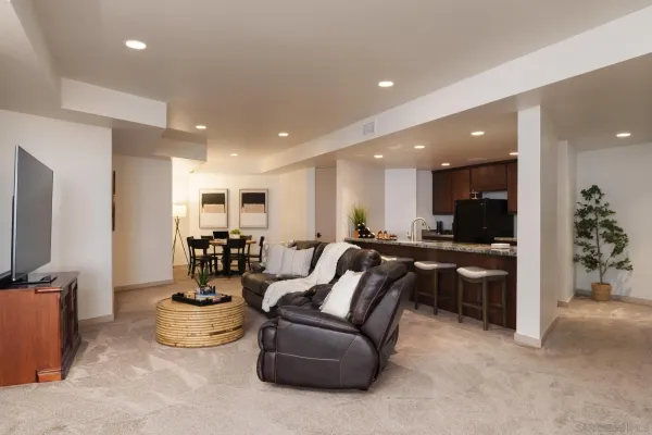 a living room with furniture a flat screen tv and kitchen view