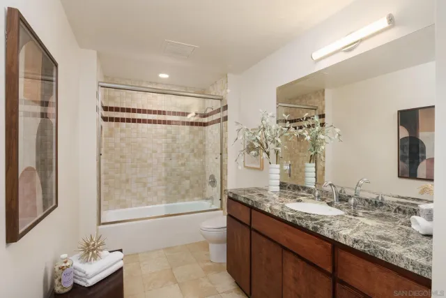 a bathroom with a granite countertop sink a mirror and a shower